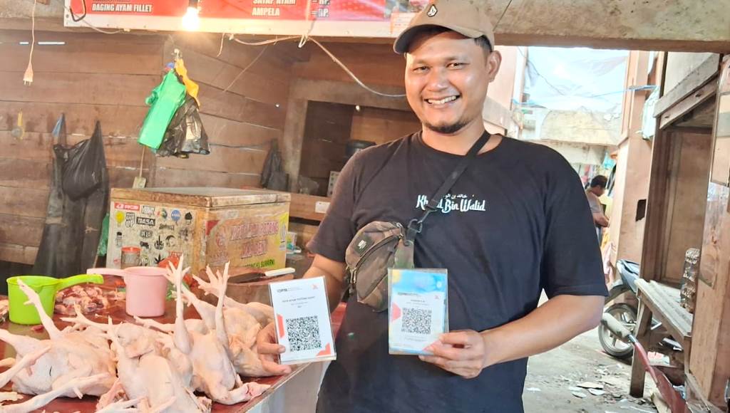 Dadang Suryama yang mengelola Kios Ayam Potong Mas Deny saat menunjukkan dua QRIS yang memudahkan transaksi dengan konsumennya